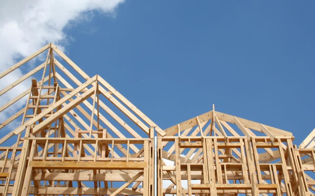 A wooden frame of a house with the sky in the background